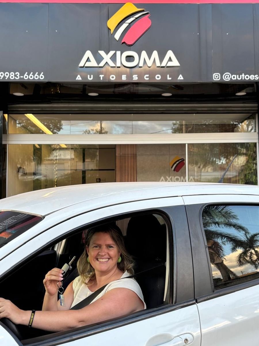 Nadia ao volante, com a chave na mão, em frente à Axioma